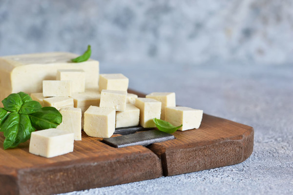 Soy cheese - classic tofu cheese on a wooden board on the kitchen table.